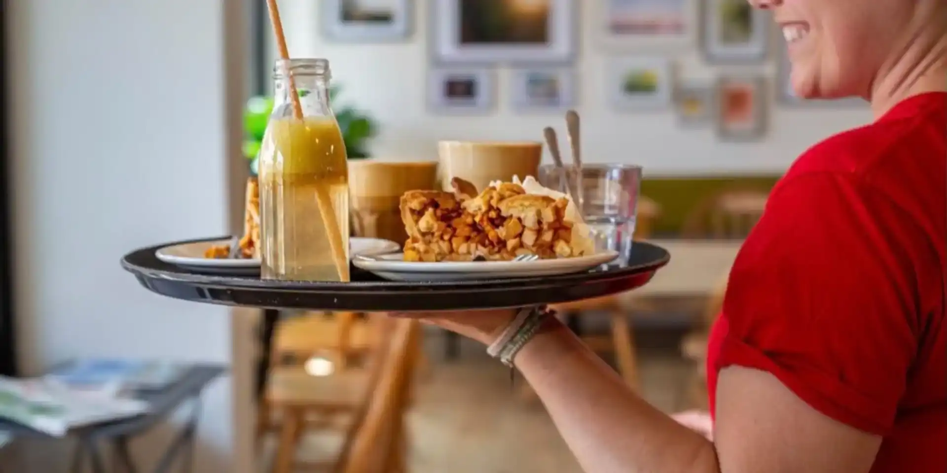 Horecamedewerker met dienblad met gebak en koffie